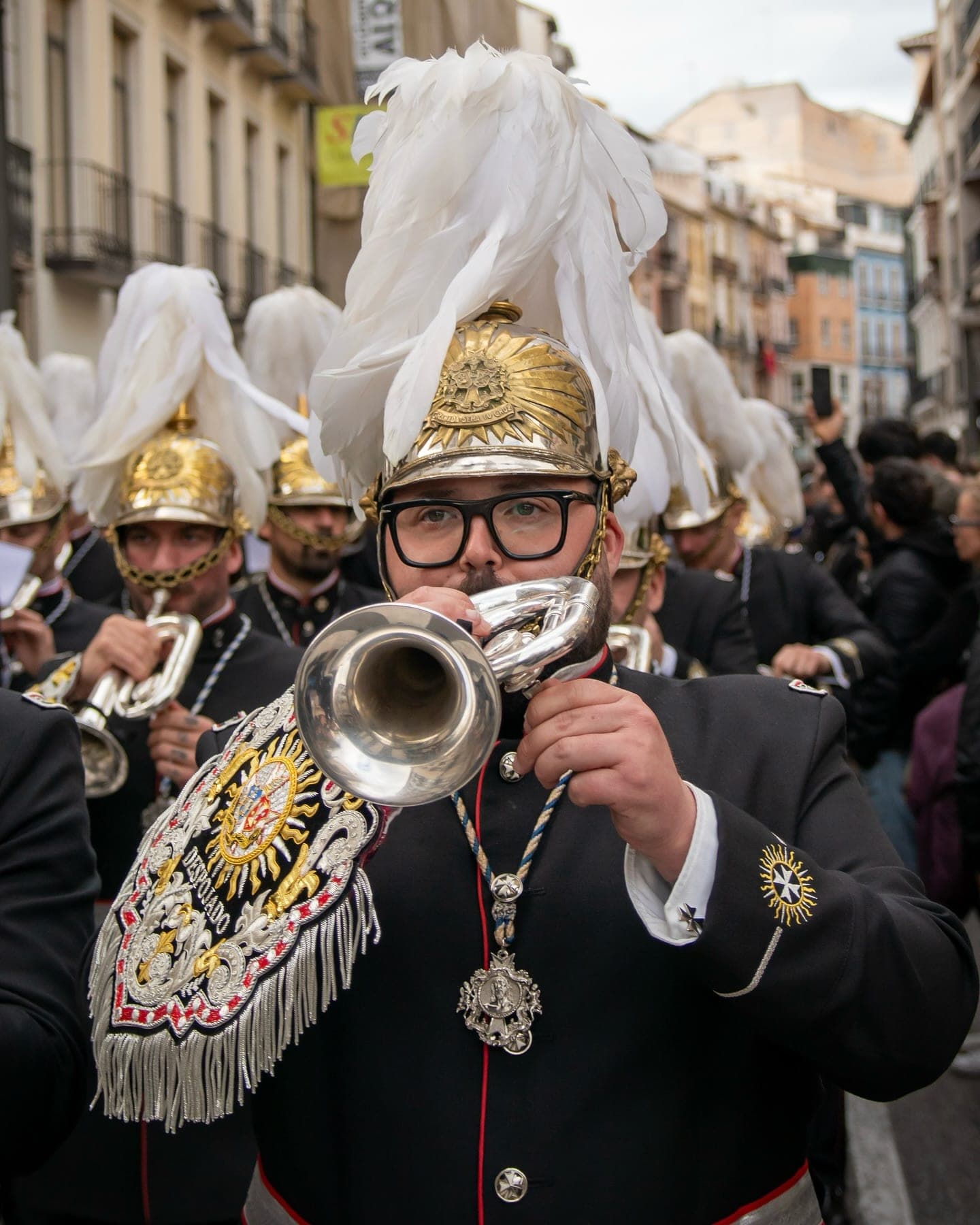 Corneta con casco de penacho blanco y mantolín, tocando en procesión