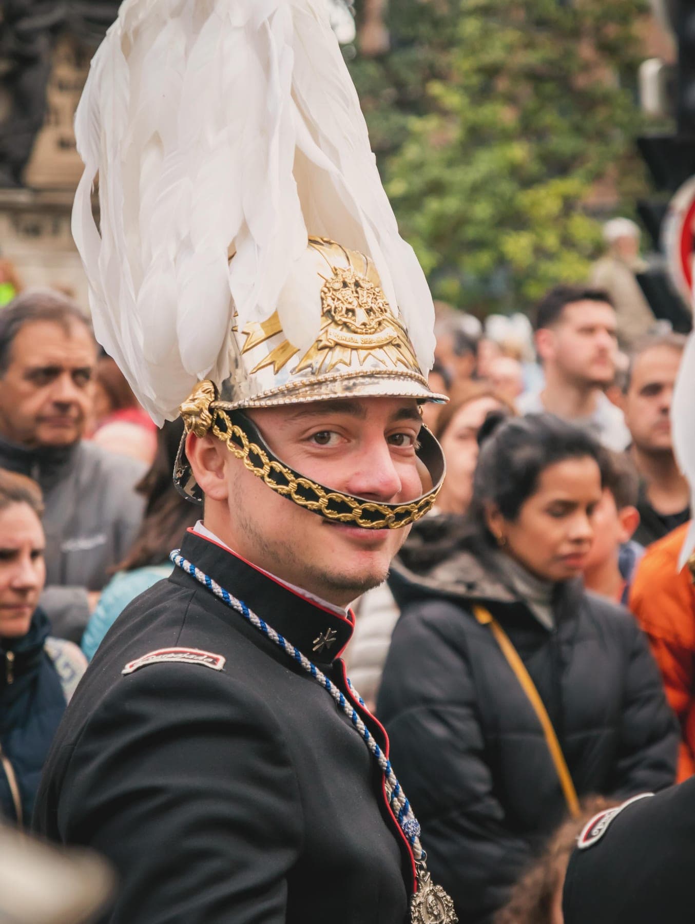 Músico de la banda con el casco dorado y el penacho, sonriendo entre el público